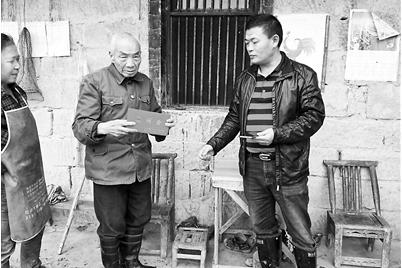 巴南区基层党员干部李永波(右)生前给贫困户送去慰问金。 记者 杨新宇 翻拍.jpg